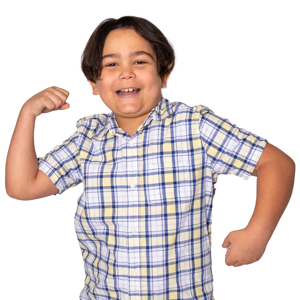 A little boy named Noah smiles at the camera, showing off his muscles in a superhero pose.