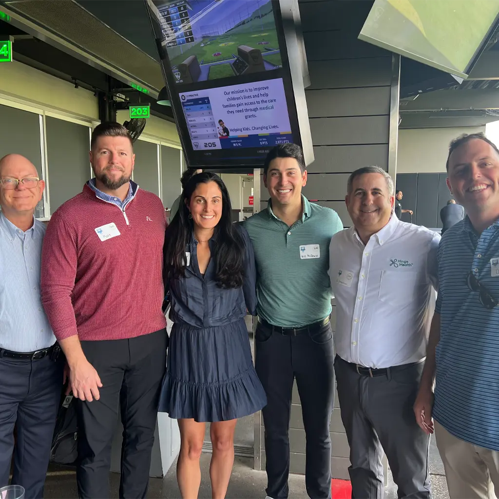 Five men and one woman pose for a picture at a Texas Top Golf event with their arms around one another.